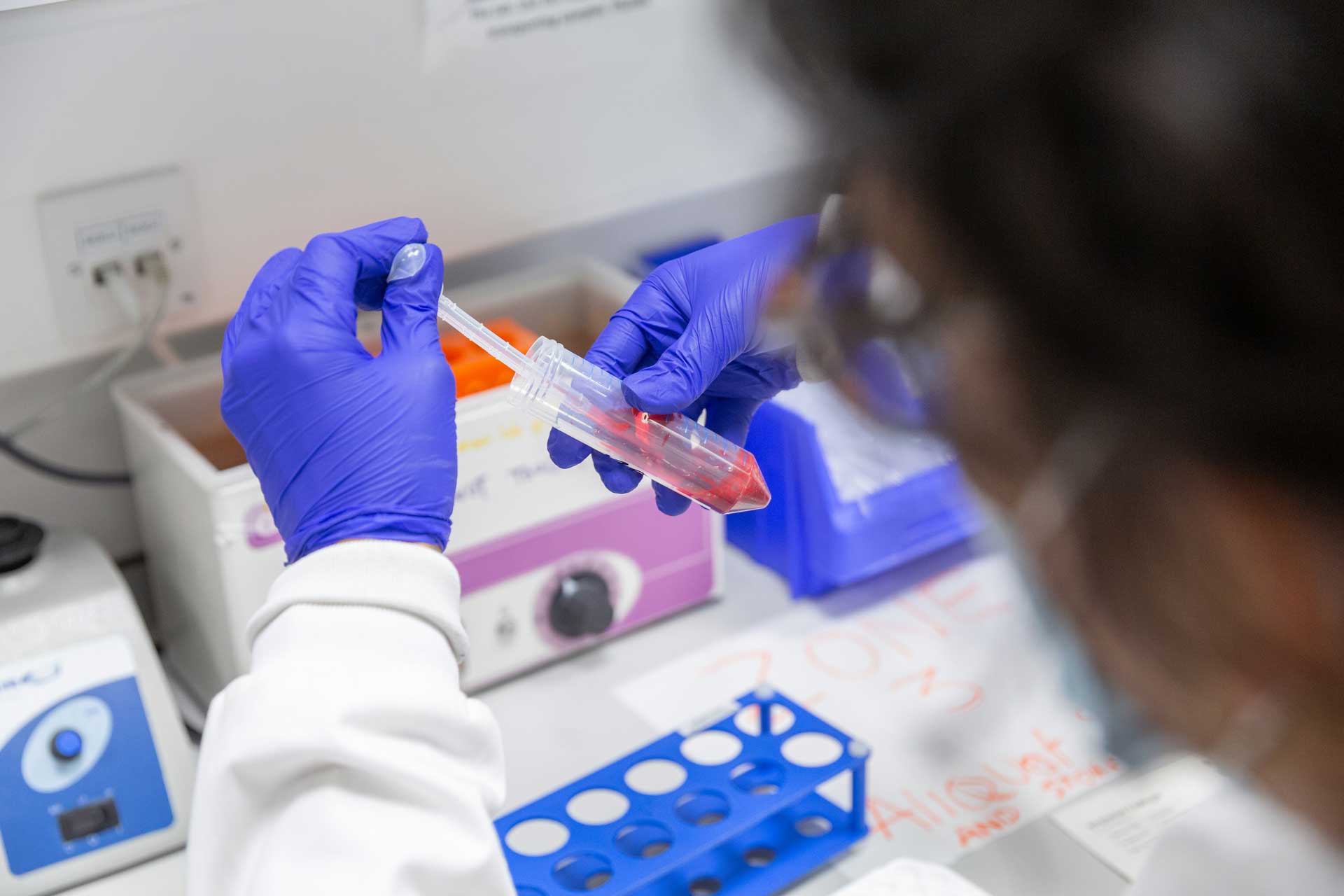 female-scientist-handling-blood-sample-wearing-purple-gloves